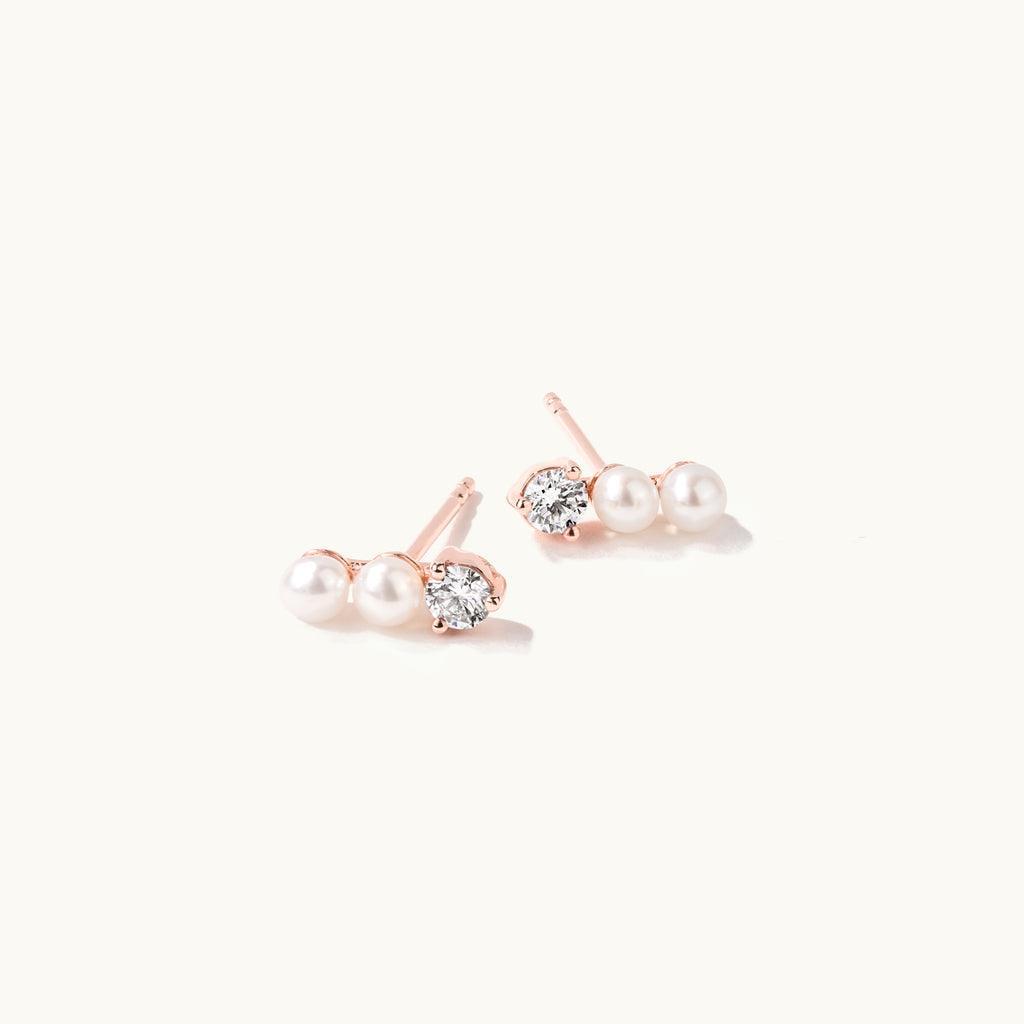 Angled view of Jewellers District's Three-Stone Pearl and Diamond Bar Earrings in 14k Rose Gold