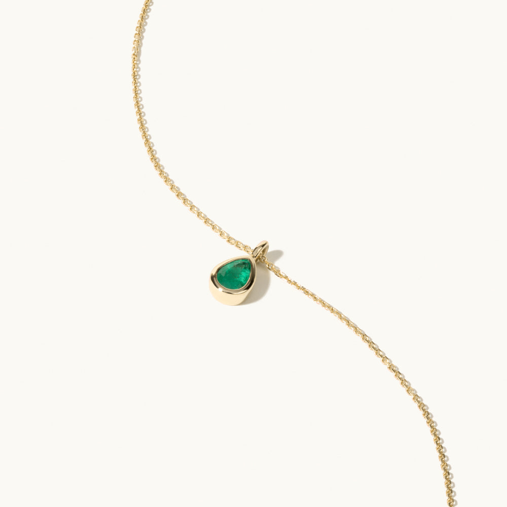 Angled view of Jewellers District's Bezel Set Pear-Cut Emerald Pendant Necklace in 14k Yellow Gold