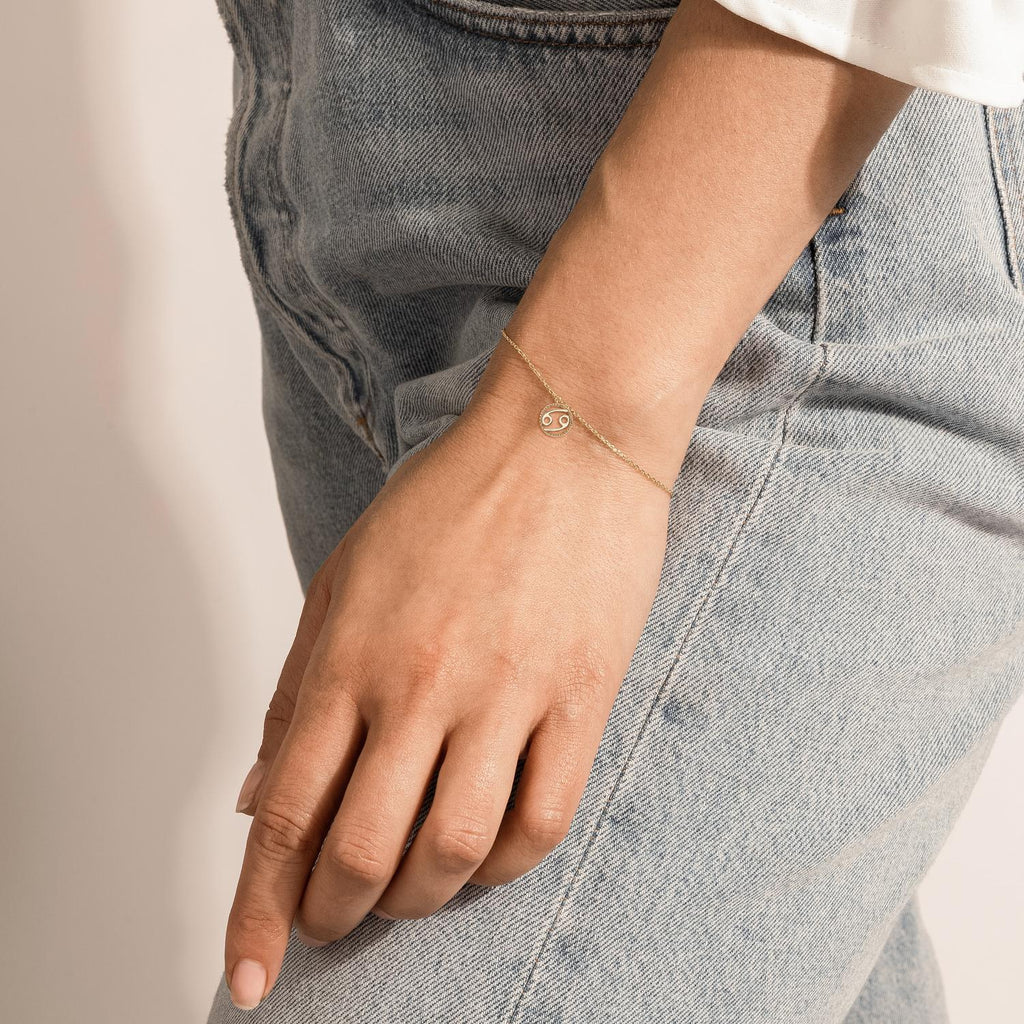 Model wearing Jewellers District's Gold Zodiac Charm Bracelet: Cancer in 10k Yellow Gold