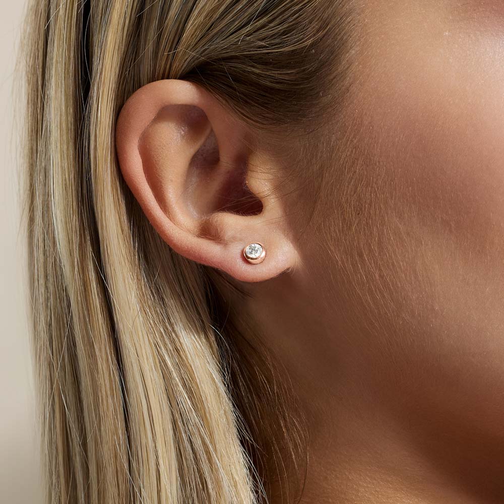 Model wearing Jewellers District's Bold Bezel-Set Round Cut Diamond Studs in 10k Rose Gold