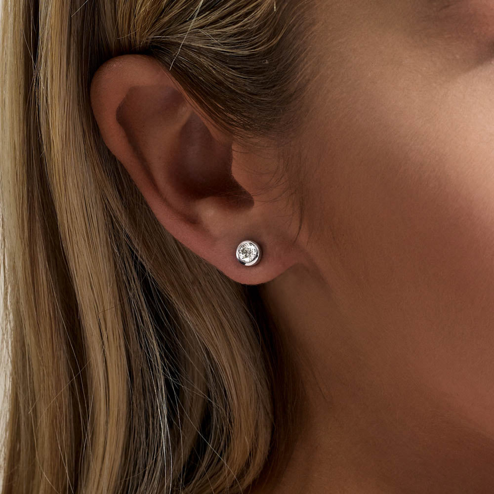 Model wearing Jewellers District's Bold Bezel-Set Round Cut Diamond Studs in 10k White Gold #4