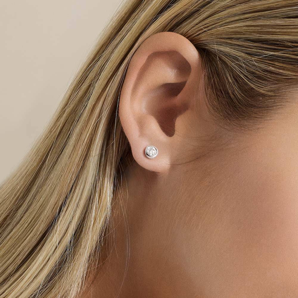 Model wearing Jewellers District's Bold Bezel-Set Round Cut Diamond Studs in 10k White Gold #2