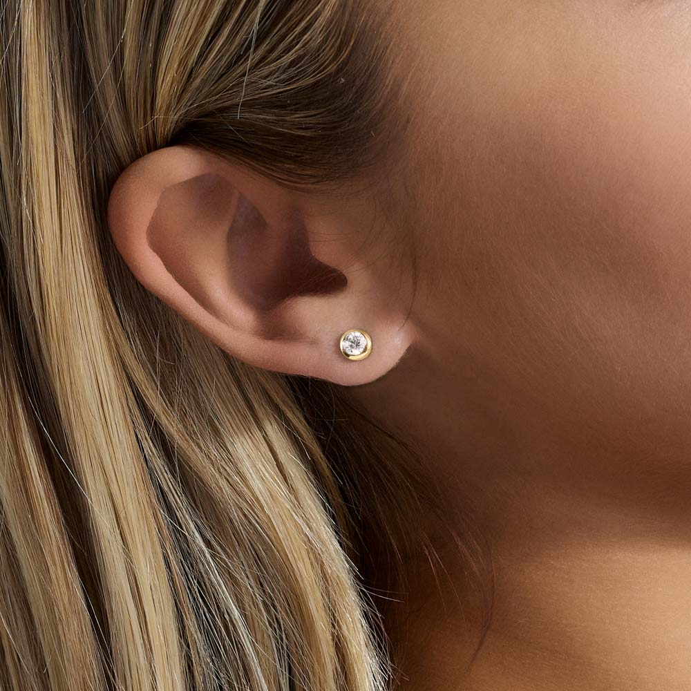 Model wearing Jewellers District's Bold Bezel-Set Round Cut Diamond Studs in 10k Yellow Gold #3