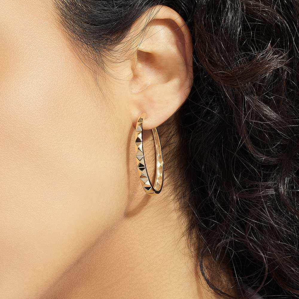 Model wearing Jewellers District's Faceted Gold Hoop Earrings in 10k Yellow Gold #3