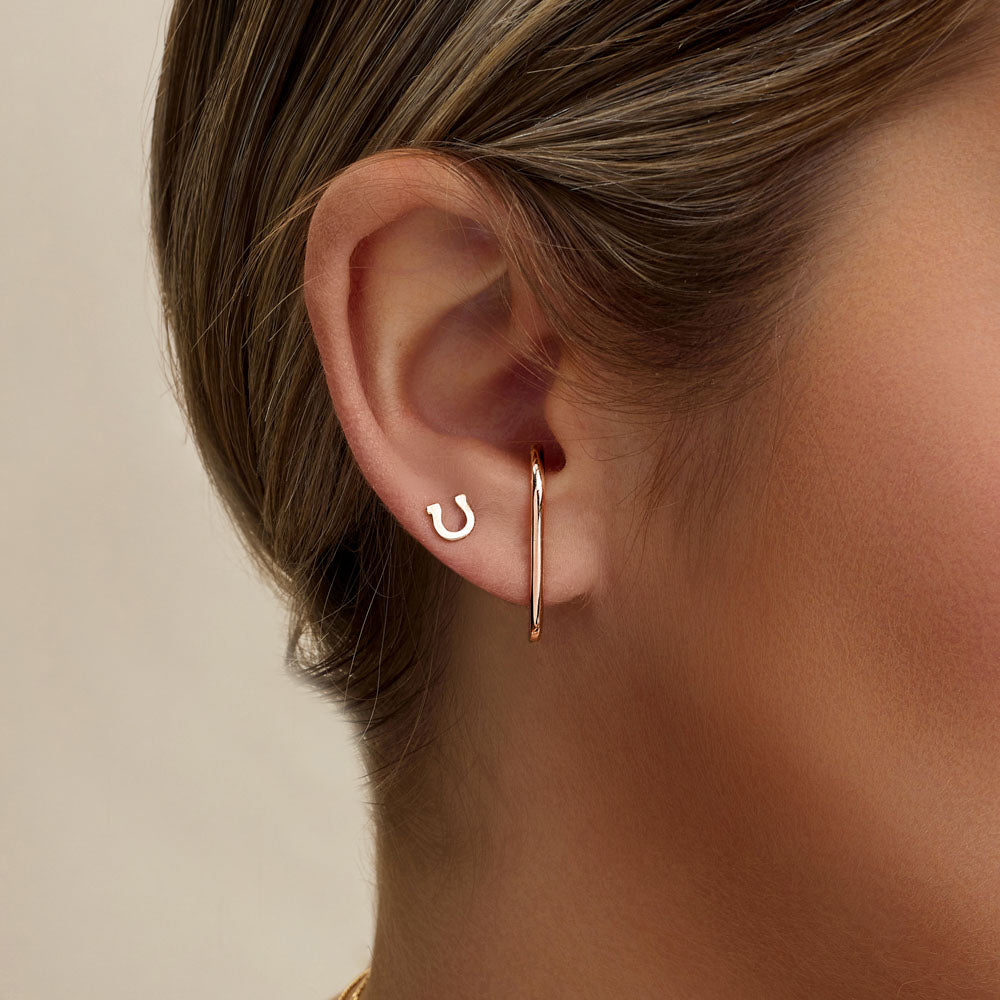 Model wearing Jewellers District's Gold Horseshoe Stud Earrings in 10k Rose Gold #2