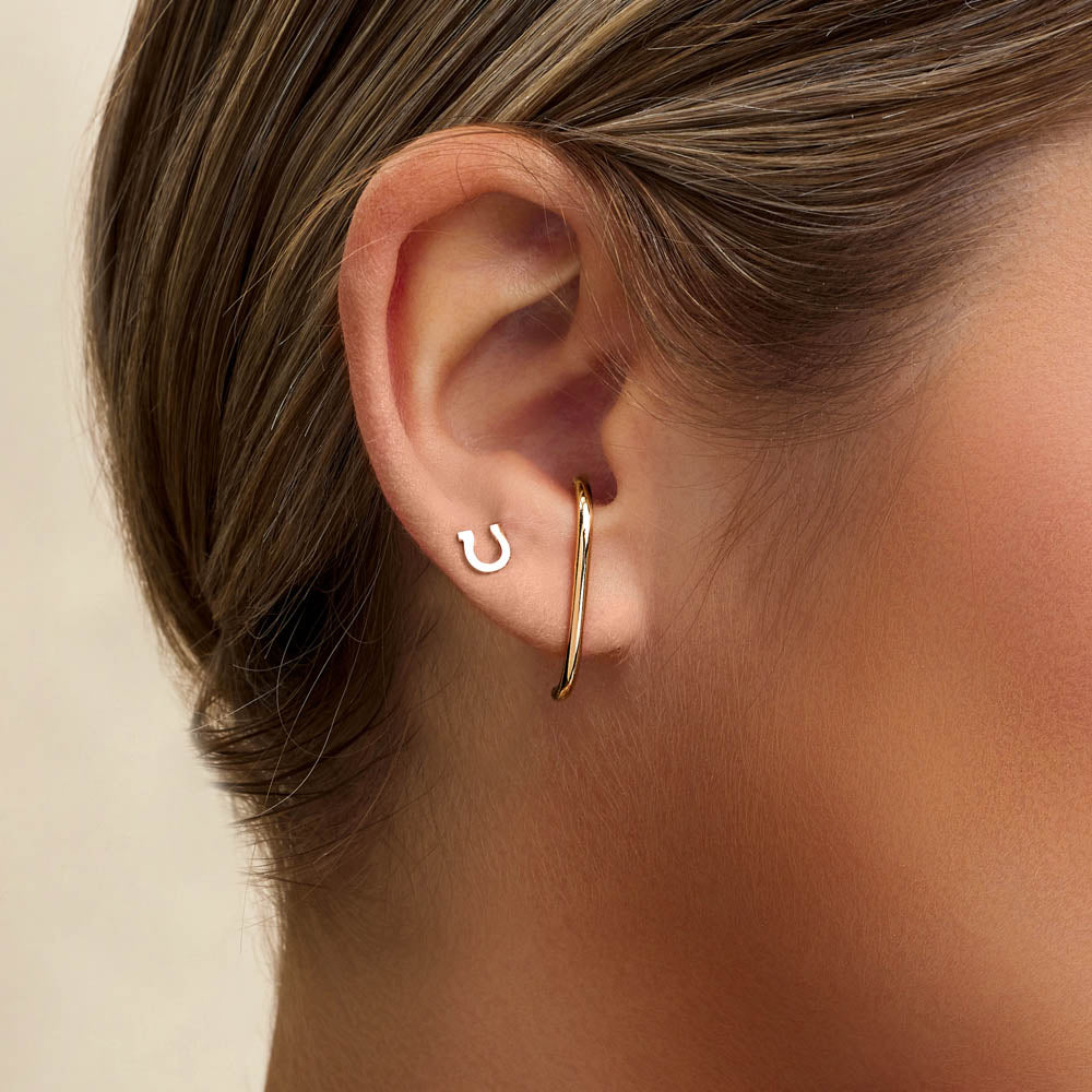 Model wearing Jewellers District's Gold Horseshoe Stud Earrings in 10k Yellow Gold #3