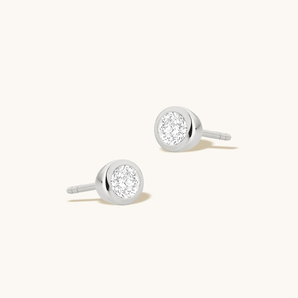 Angled view of Jewellers District's Bold Bezel-Set Round Cut Diamond Studs in 10k White Gold