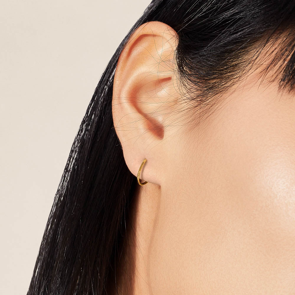 Model wearing Jewellers District's Petite Gold Hoop Earrings in 14k Yellow Gold #2