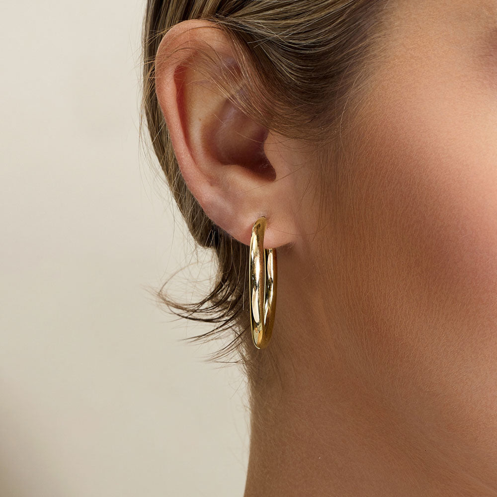 Model wearing Jewellers District's Gold Hoop Earrings in 10k Yellow Gold #2