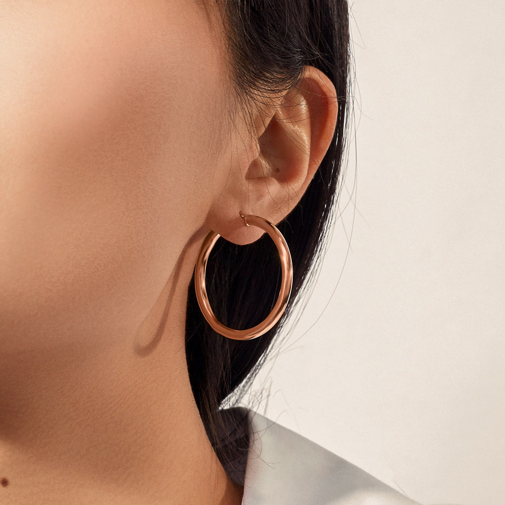 Model wearing Jewellers District's Thin Gold Hoop Earrings in 10k Rose Gold