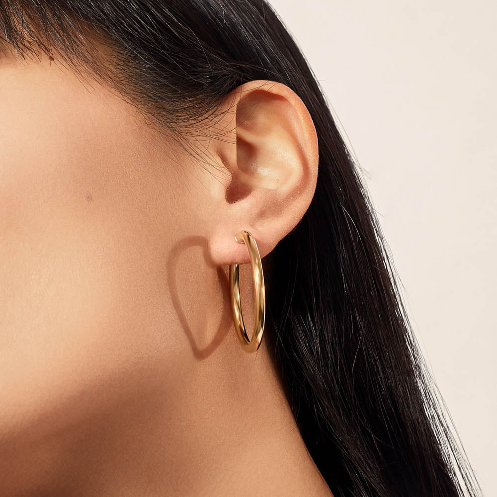 Model wearing Jewellers District's Thin Gold Hoop Earrings in 10k Yellow Gold #2