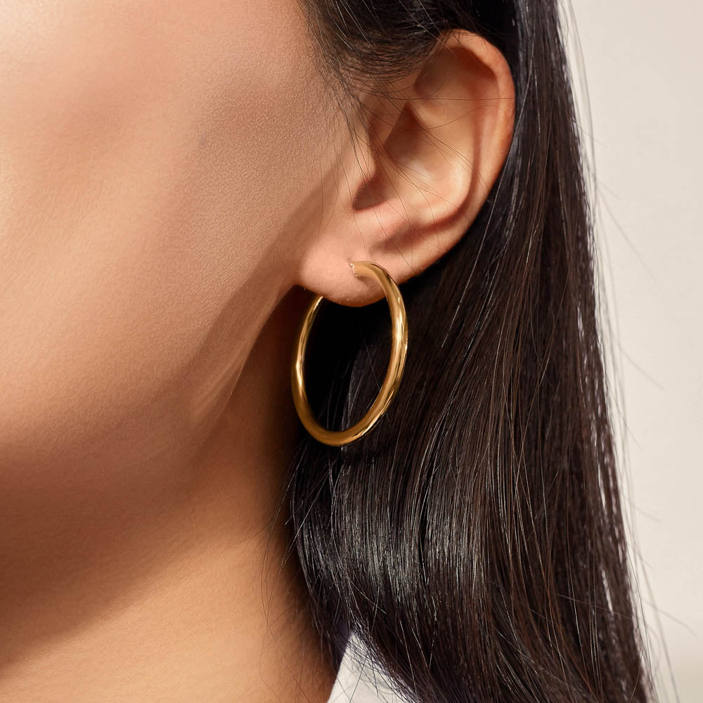 Model wearing Jewellers District's Thin Gold Hoop Earrings in 10k Yellow Gold #3