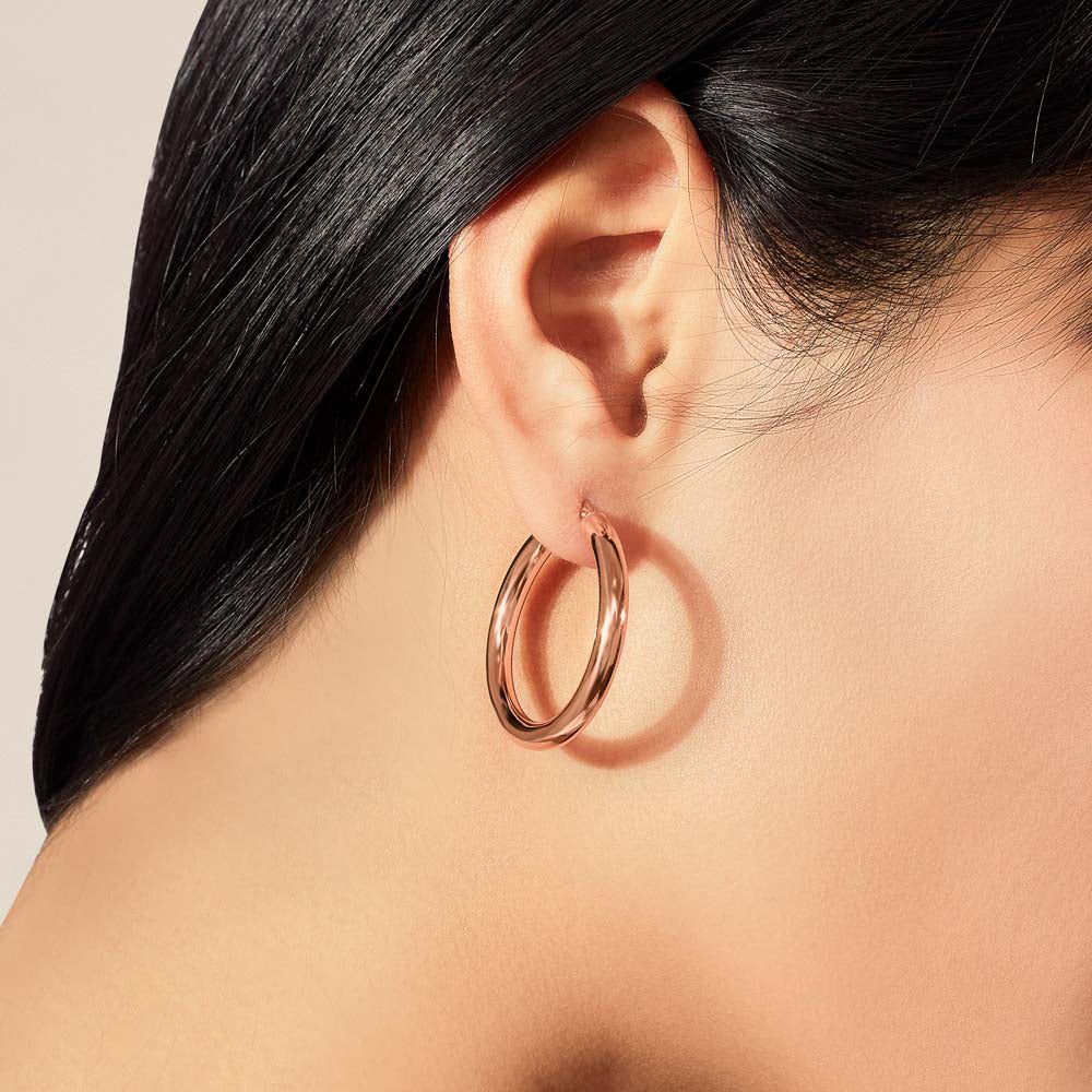 Model wearing Jewellers District's Thick Gold Hoop Earrings in 10k Rose Gold #2